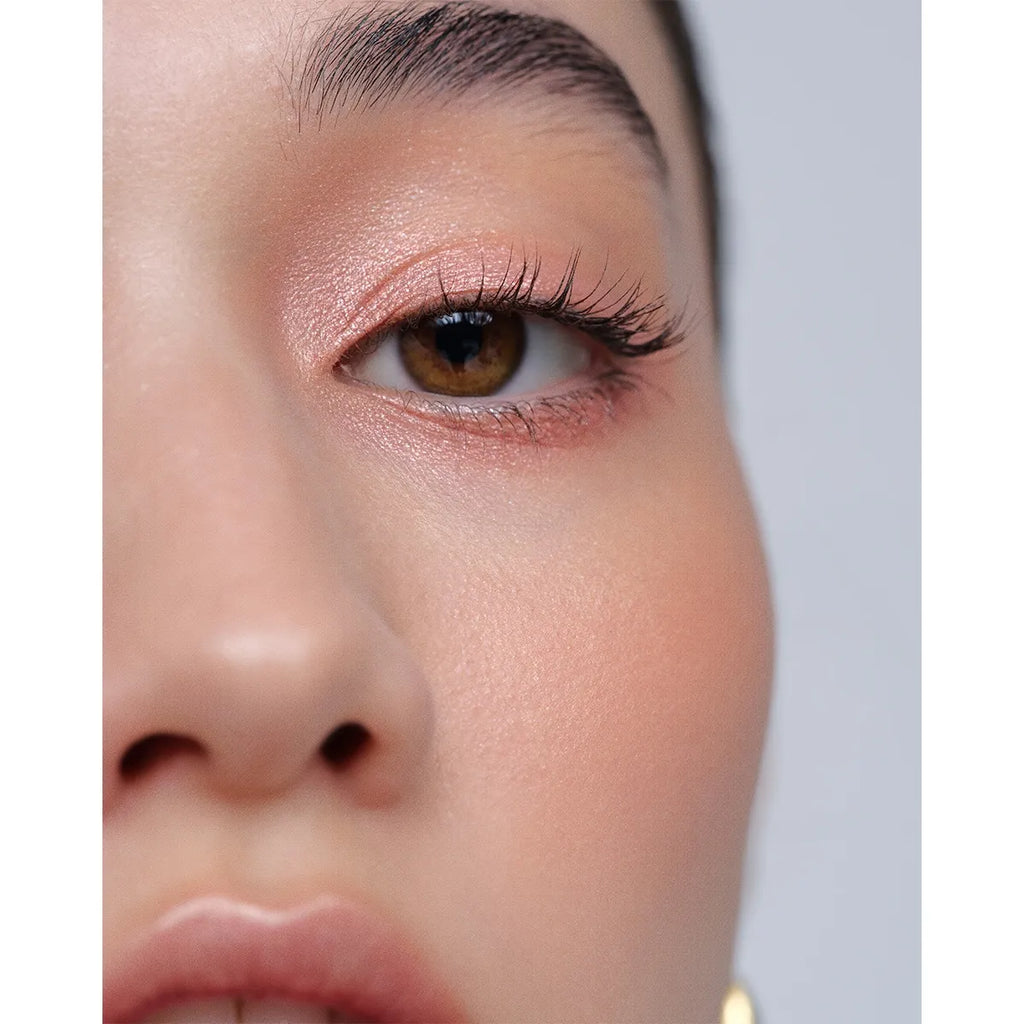 Close-up of a model wearing Addiction The Creamy Stick Eyeshadow in peachy nude, highlighting a radiant and soft eye makeup style.