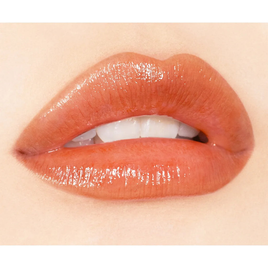 Close-up of lips wearing Addiction Tokyo Lip Balm Glow Tint in a peachy shade, showcasing a glossy, hydrated finish.