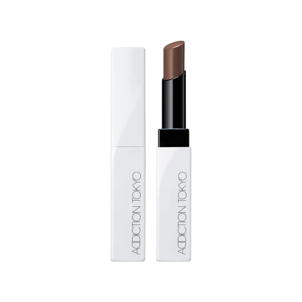 Addiction Tokyo Lip Balm Glow Tint in a brownish nude shade, featuring a modern white and black tube for a natural glossy finish.