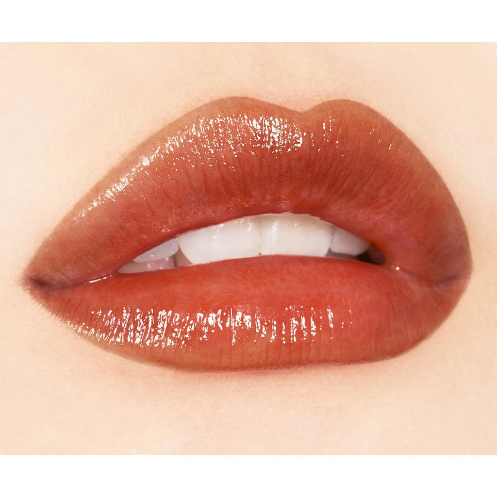 Close-up of lips wearing Addiction Tokyo Lip Balm Glow Tint in a warm brown shade, highlighting a radiant, glossy finish.