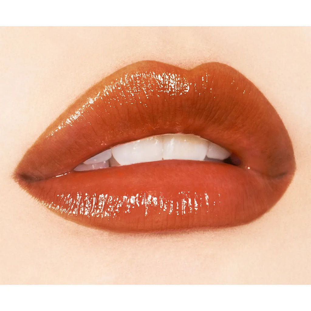 Close-up of lips wearing Addiction Tokyo Lip Balm Glow Tint in a deep brown shade, emphasizing a bold, glossy texture.