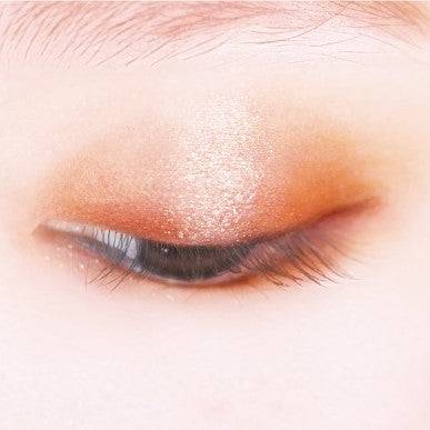 Close-up of an eyelid wearing Canmake Silky Flare Eyes matte type eyeshadow in warm brown and glittery beige tones for a radiant finish.