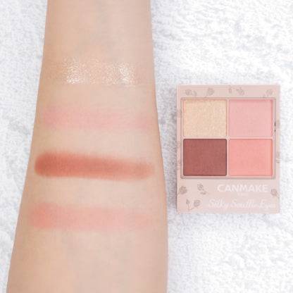 Swatches of Canmake Silky Flare Eyes matte type palette on an arm, showcasing coral, pink, and brown shades alongside the palette.