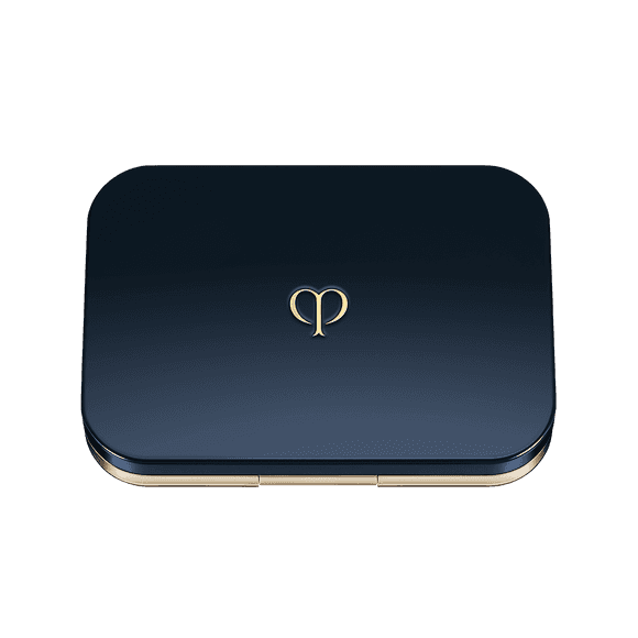 An empty Clé de Peau Beauté foundation compact case in gold and navy, designed for refillable powder foundation inserts.