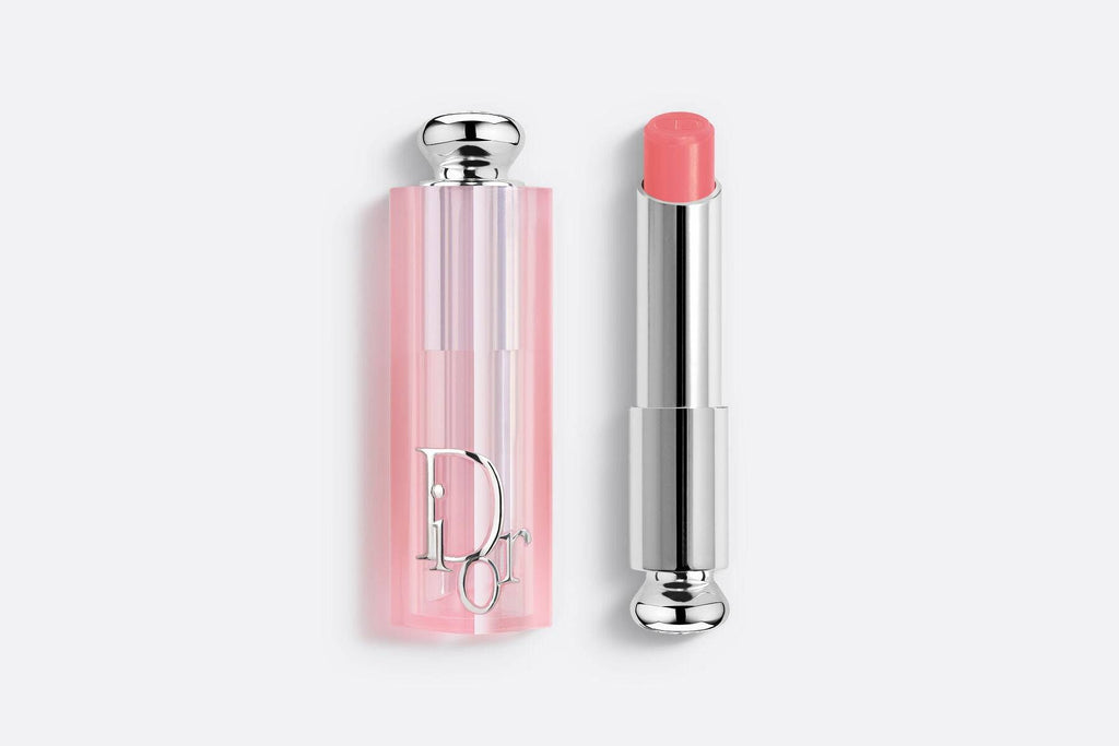 Dior Addict Lip Glow lipstick in a peachy nude shade, providing a natural, hydrating finish. Encased in a stylish pink translucent tube.