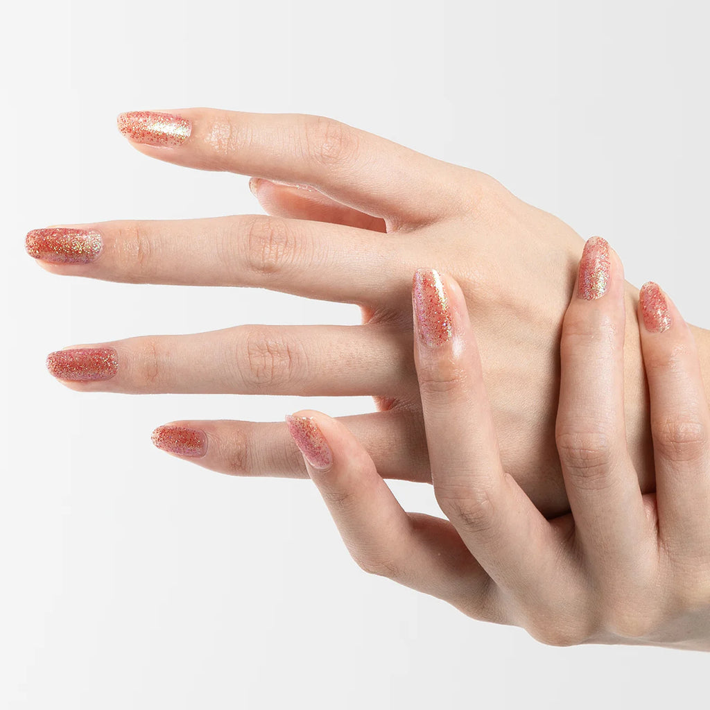 Hands with nails painted in glittery red and green Elégance Lacquer, featuring a sparkling finish for holiday-inspired looks.