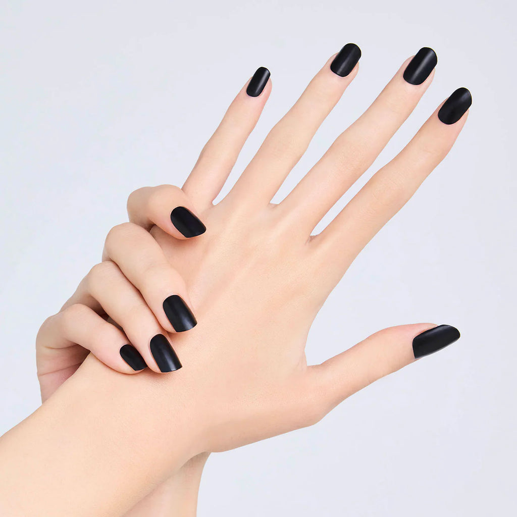 Hands with nails painted in matte black Elégance Lacquer, showcasing a bold and edgy finish for contemporary styles.