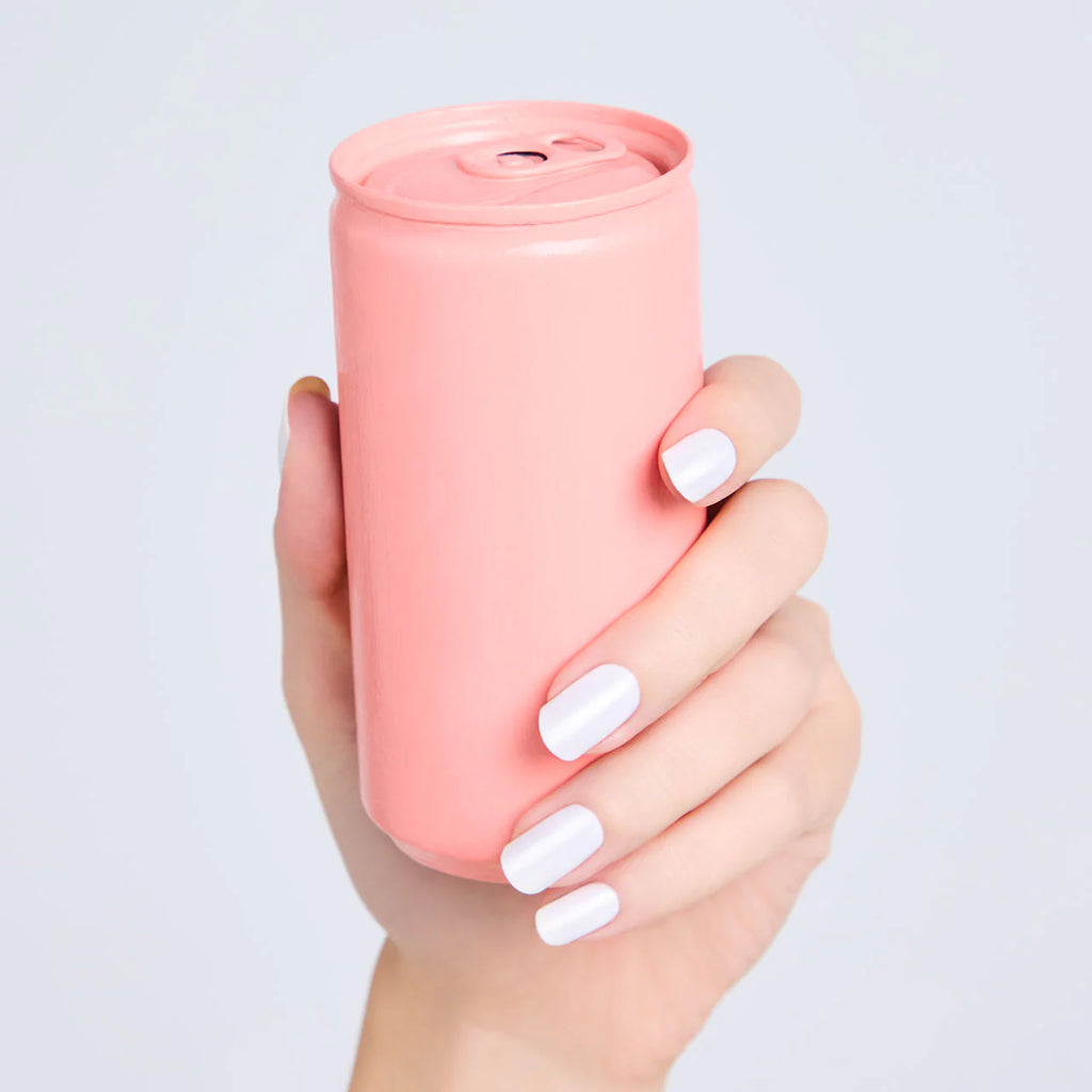 Hand with nails painted in crisp white Elégance Lacquer, holding a pink can, showcasing a smooth and modern finish.