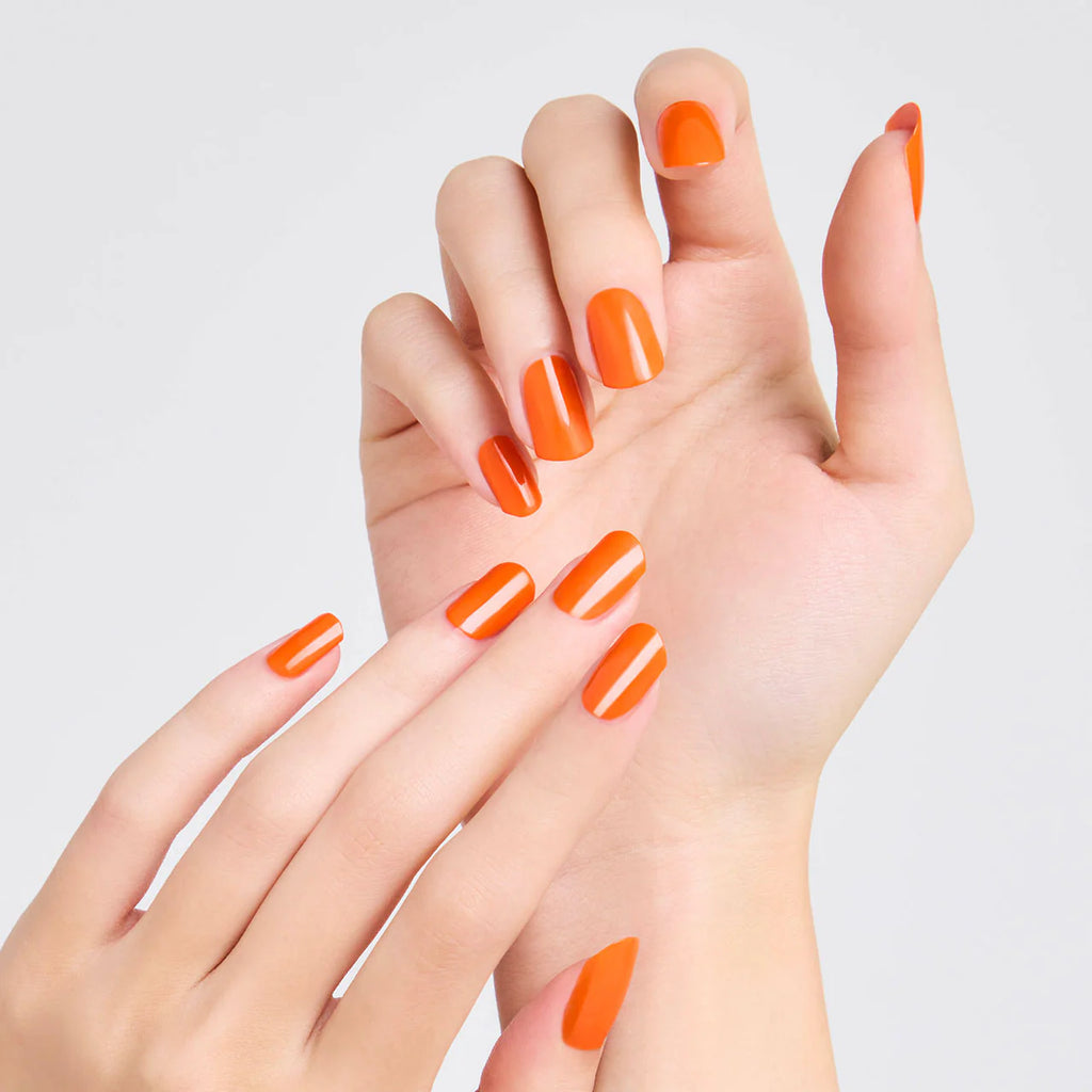 Hands with nails painted in vibrant orange Elégance Lacquer, showcasing a bold and lively finish for standout styles.