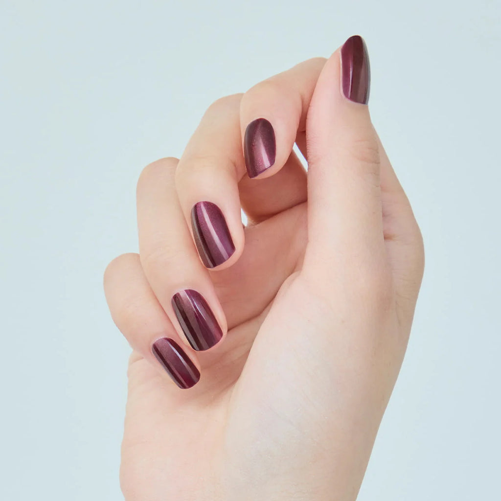 Hand with nails painted in deep metallic burgundy Elégance Lacquer, highlighting a rich and glossy finish for elegant styles.