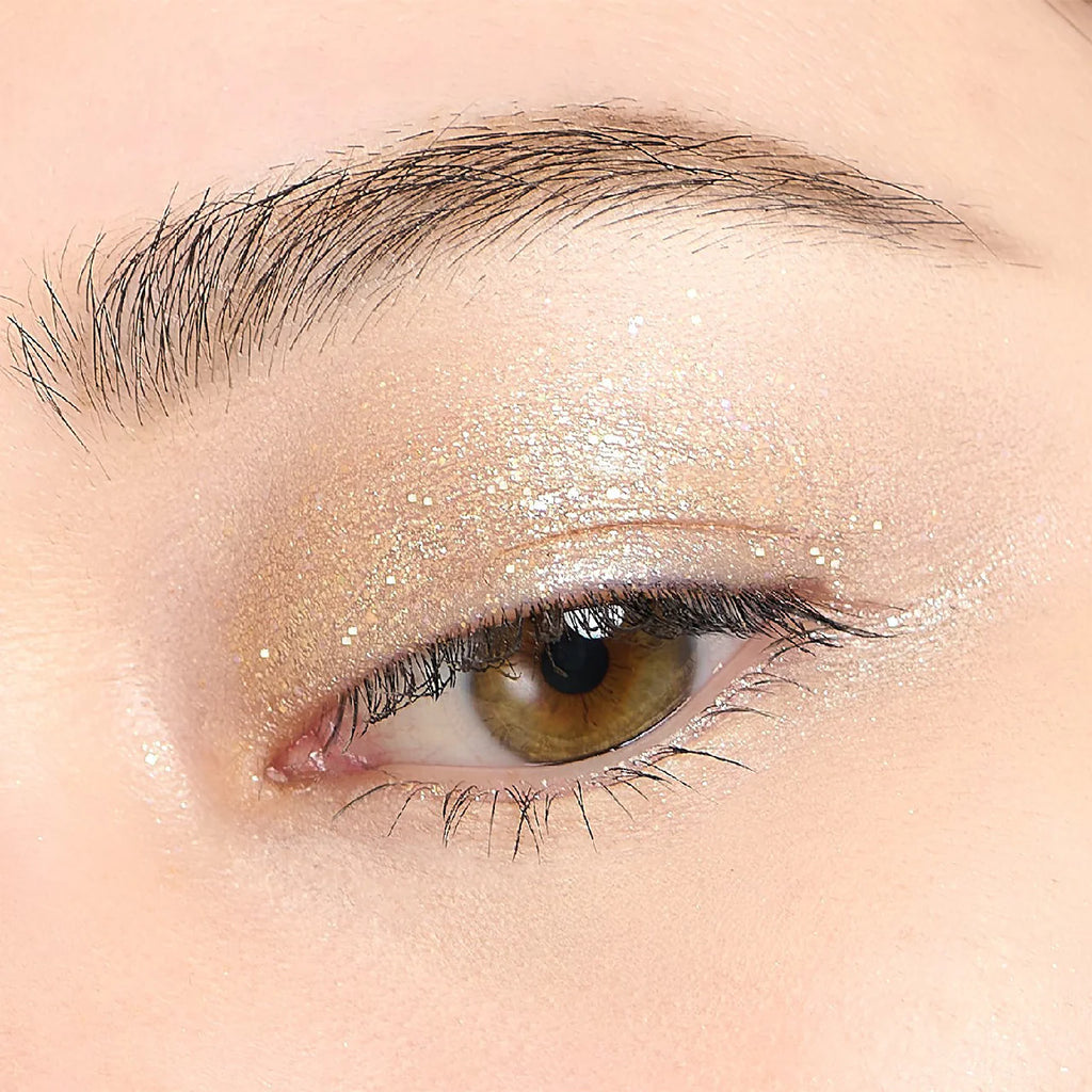 Close-up of an eyelid adorned with Elégance Razzle Eye Color in holographic gold, offering a sparkling and luminous eye makeup finish.