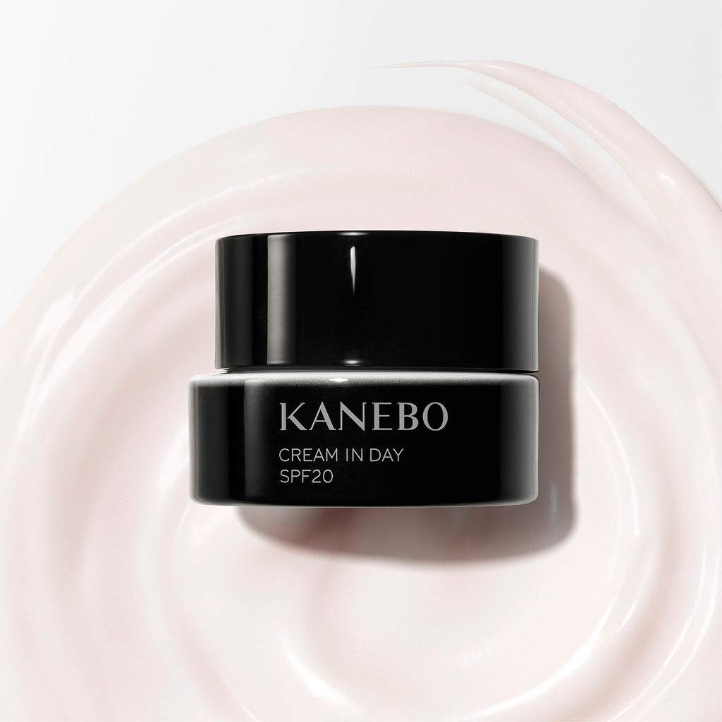 Kanebo Cream in Day 40g SPF20 jar placed on a smooth swirl of cream, emphasizing its luxurious texture and moisturizing benefits.