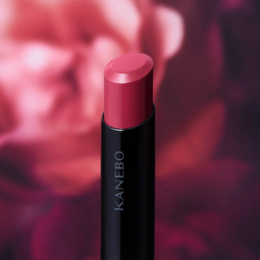 Kanebo Rouge Star Vibrant lipstick in a berry tone, set against a floral-inspired background with a luminous finish.