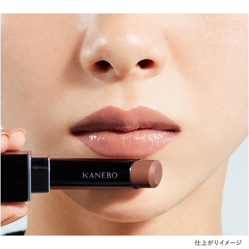 Model applying Kanebo Rouge Star Vibrant lipstick in a deep brown shade, highlighting a glossy and bold finish.