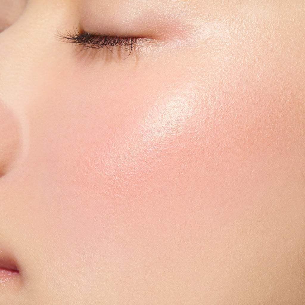 Close-up of a model's cheek showcasing the coral pink shade of Lunasol Coloring Sheer Cheeks (Glow) for a natural glow.