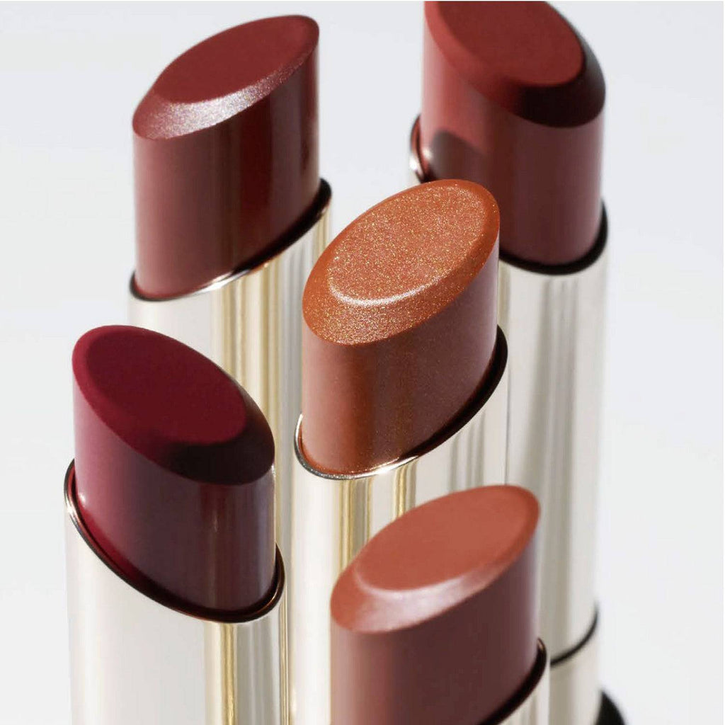 Assorted RMK Dewy Melt Lip Color lipsticks in various shades, showcasing their glossy finishes and luxurious gold packaging.