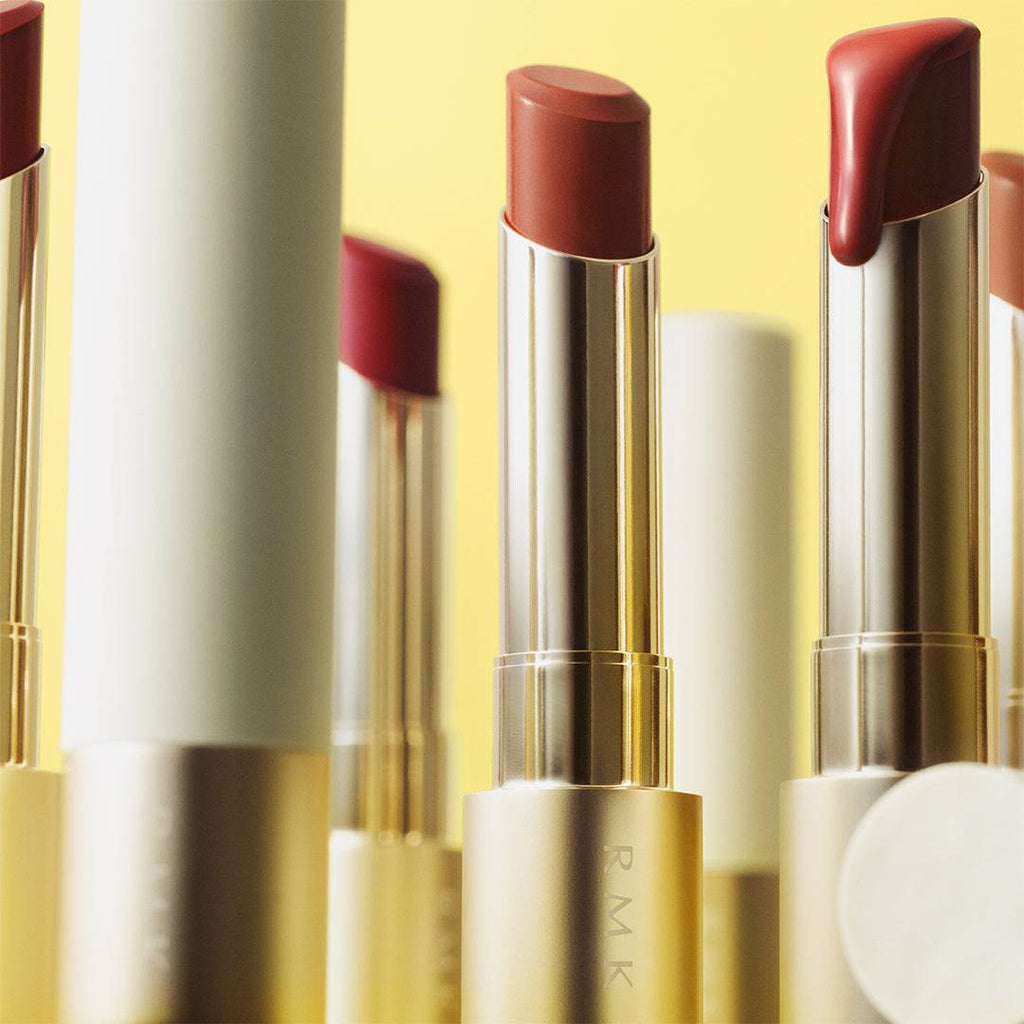 RMK Dewy Melt Lip Color collection displayed against a yellow background, highlighting the vibrant shades and sleek packaging.