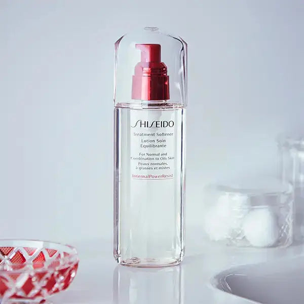 Shiseido Treatment Softener 150ml bottle with red pump displayed on a bathroom counter, surrounded by skincare accessories.