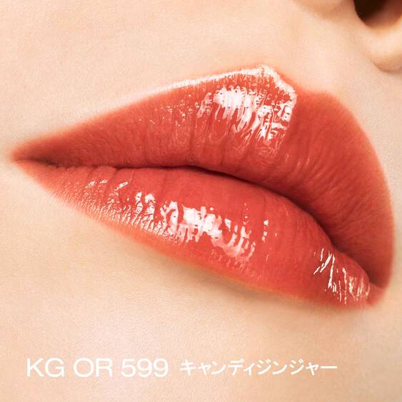 Close-up of lips wearing Shu Uemura Kinu Care Glow Up lip gloss in KG OR 599 Candy Ginger, highlighting a glossy, bright orange finish.