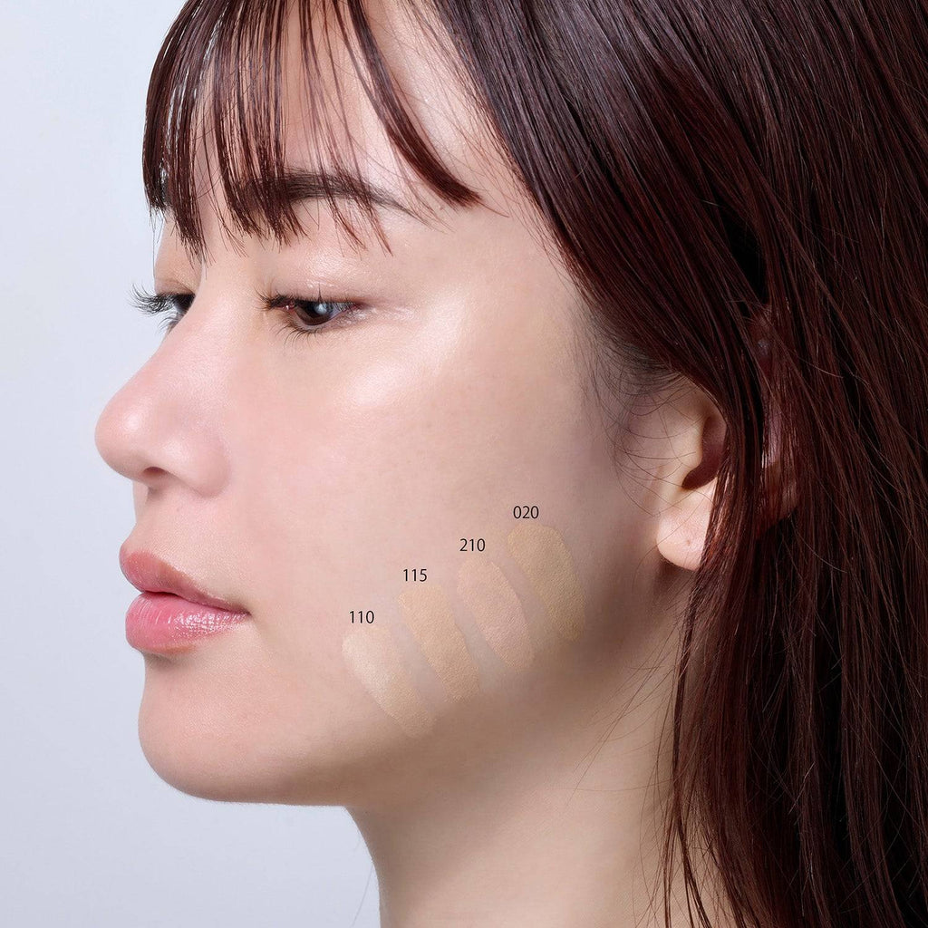 Profile view of a model with Suqqu The Foundation 30g swatches in shades 110, 115, 210, and 020 applied on the cheek.