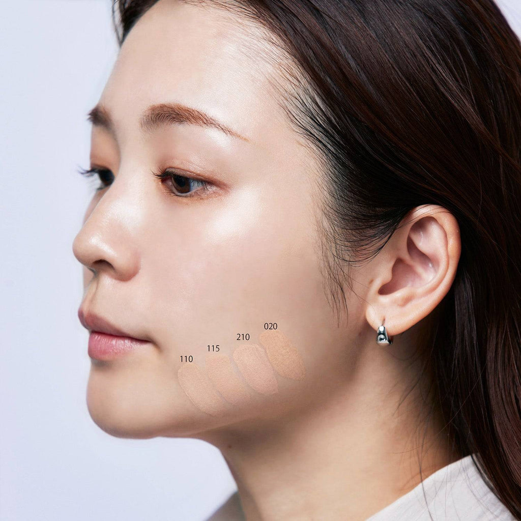 Suqqu The Foundation 30g swatches on a woman's jawline showcasing shades 110, 115, 210, and 020. Cream makeup with a rich glossy glow for flawless skin.