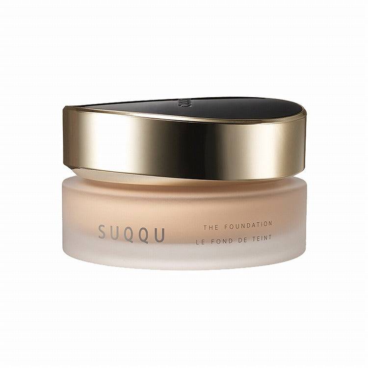 Suqqu The Foundation 30g in a frosted jar with a gold and black lid, offering SPF protection and a rich glossy glow.