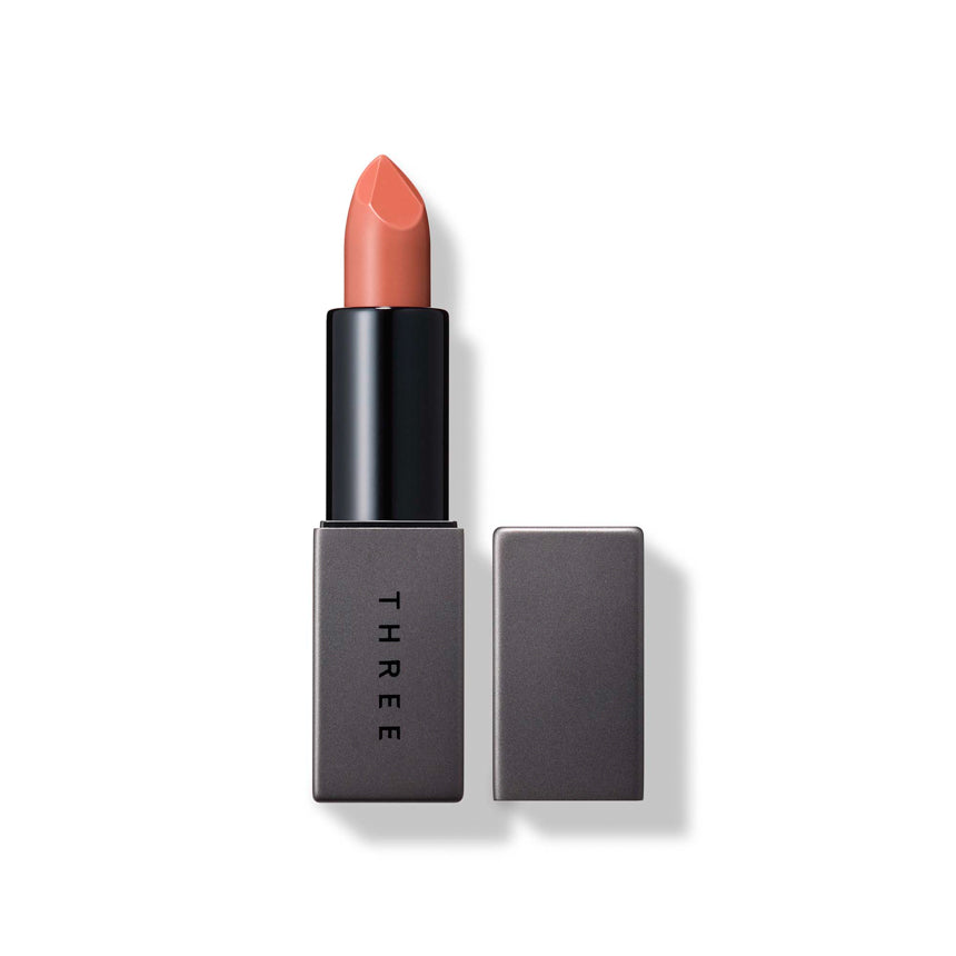 Three Dream On Alluring Lip Stick in shade 01 Eternal Flux, a warm peach tone with a sleek gray case. Ideal for subtle lip makeup.