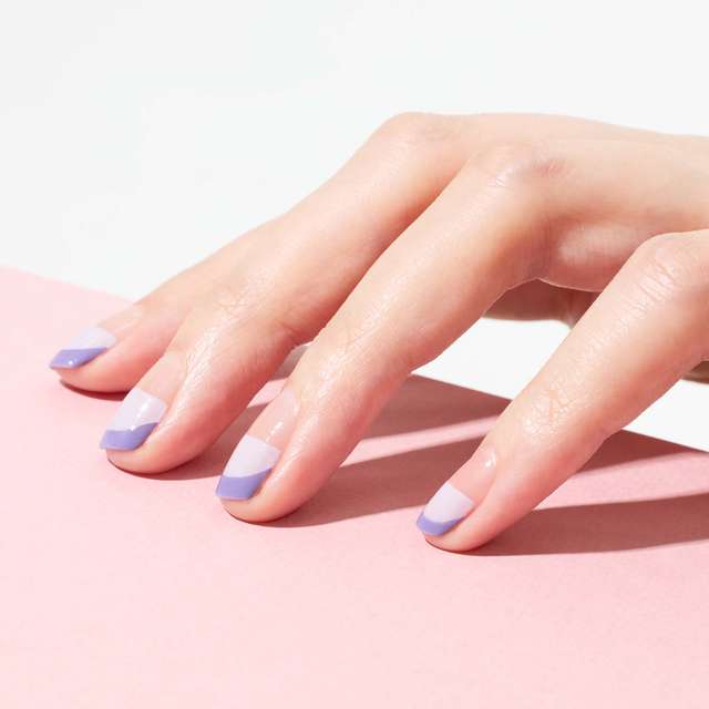 Hand with nail art featuring Three Nail Lacquer in lilac and lavender shades, creating a soft and elegant design.