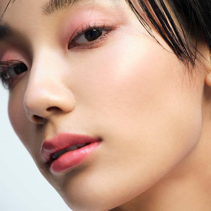 Model wearing Three Glam Tone Color Custard in a vibrant red shade, emphasizing its multi-use versatility for a bold makeup look.